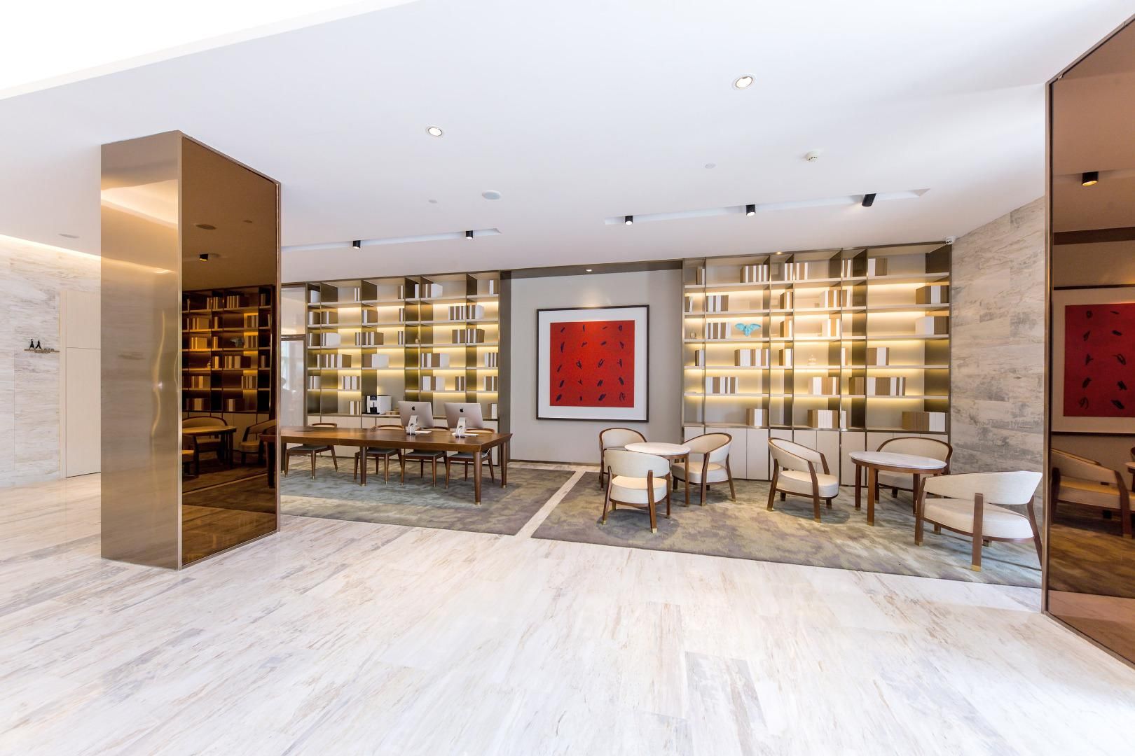 A modern library with bookshelves, a dining area with tables and chairs, and a large red artwork on the wall.