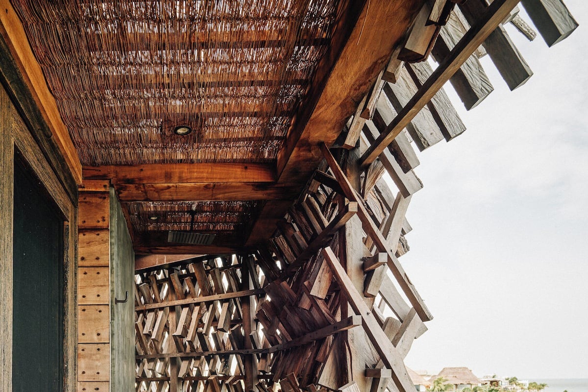 Una escalera de madera que lleva a un balcón con vistas a palmeras y al océano.