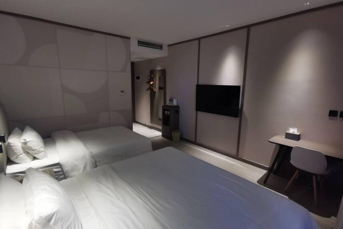A modern hotel room with a large bed, a desk, and a TV.
