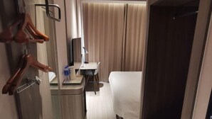 A hotel room with a bed, a desk with a chair, a mirror, and a wardrobe. - HanTing Hotel (Eye of Tianjin) (Tianjin)