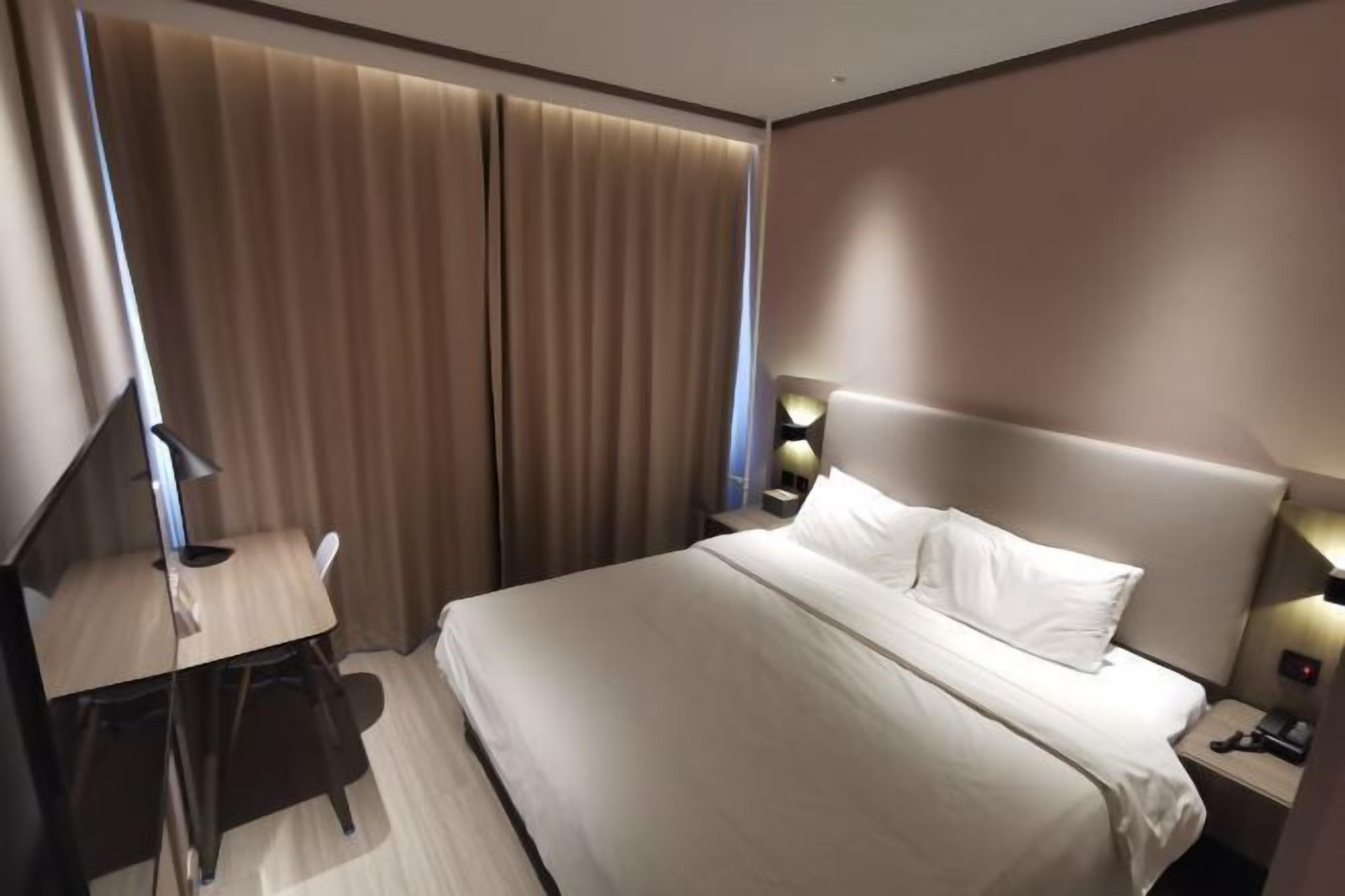 Ein Hotelzimmer mit Bett, Schreibtisch und Vorhängen.