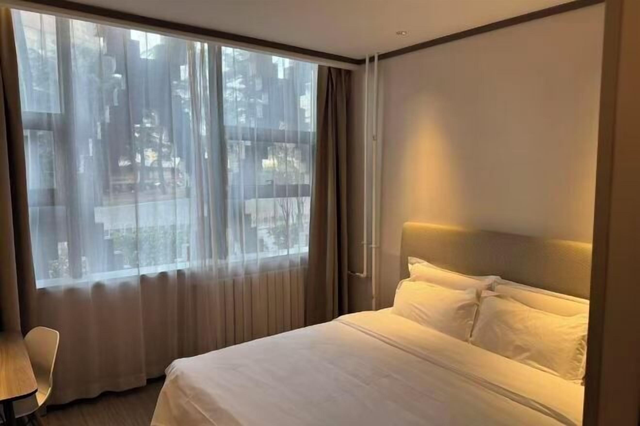 Ett hotellrum med ett stort fönster, en säng och en stol.