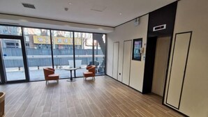 A spacious room with a large window, a small table, two chairs, and a door leading to an elevator. - HanTing Hotel (Eye of Tianjin) (Tianjin)
