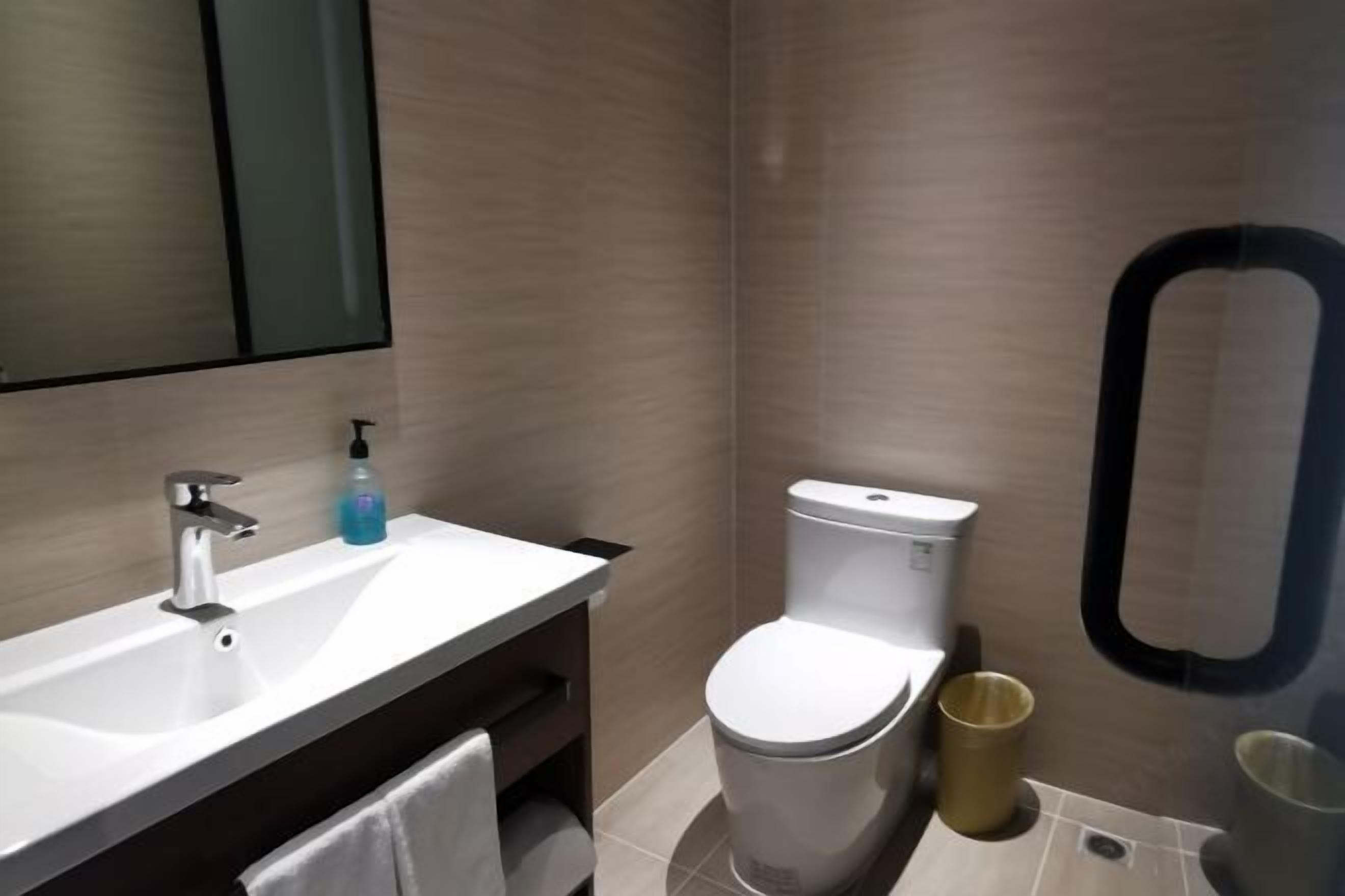 A modern bathroom with a white sink, a toilet, and a mirror.