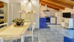 A modern kitchen with blue tiles, a dining area with a table and chairs, and a TV on a stand. - St. Francis apartment (Agropoli)
