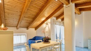 A dining area with a wooden table and chairs, a blue sofa, and a potted plant. - St. Francis apartment (Agropoli)