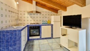 A kitchen with blue tiles, a stove, oven, and a TV. - St. Francis apartment (Agropoli)