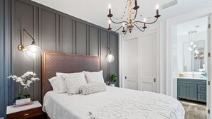 A bedroom with a large bed, a nightstand with a lamp, a dresser, and a mirror. - GORGEOUSLY RENOVATED! Palms C15, Gulf-Front,CORNER-UNIT, MODERN & FACING SUNSET! (Santa Rosa Beach)
