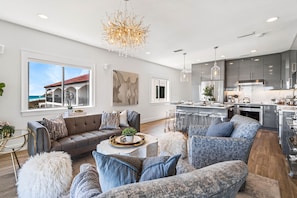 A modern living room with a sectional sofa, a coffee table with decorative items, and a view of the ocean through large windows.