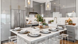 A modern kitchen with stainless steel appliances, a marble countertop, and clear glass pendant lights. - GORGEOUSLY RENOVATED! Palms C15, Gulf-Front,CORNER-UNIT, MODERN & FACING SUNSET! (Santa Rosa Beach)