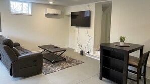 Un salon moderne avec un canapé d’angle, une petite table et un téléviseur fixé au mur.