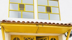 A two-story building with yellow-framed windows and a tiled roof. - Boho Tavira Apartment (Tavira)