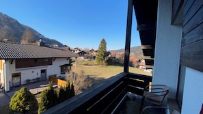 Ein Balkon mit Blick auf ein Dorf, ein Berg im Hintergrund und ein klarer Himmel.