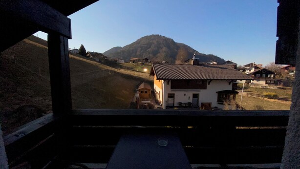 Bergzicht vanaf een balkon met een huis en een berg op de achtergrond.