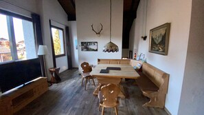 Ein Essbereich mit Holztisch und -stühlen, einem Fernseher und einer Pendelleuchte.