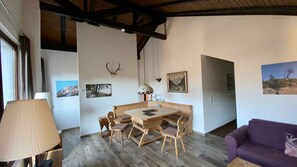 Ein Essbereich mit Holztisch und -stühlen, einer Lampe und Bildern an der Wand.