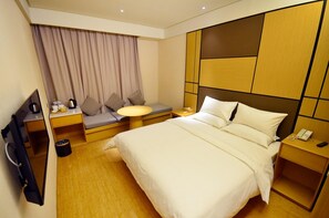 A hotel room with a bed, a seating area with a table, a TV, and a desk. - Ji Hotel (Wuhan)