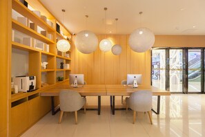 A modern office space with a long wooden table, two grey chairs, and a bookshelf with various items. - Ji Hotel (Wuhan)