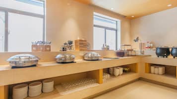 Disposição de buffet com várias estações de serviço, incluindo pratos tampados e utensílios.
