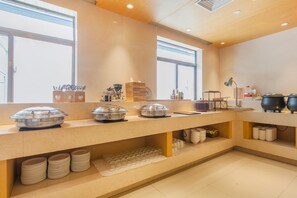 A buffet setup with multiple serving stations, including covered dishes and utensils. - Ji Hotel (Wuhan)