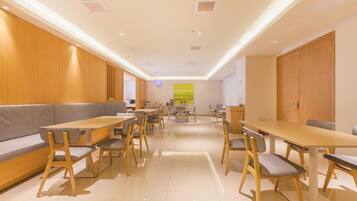 A modern dining area with wooden furniture, recessed ceiling lights, and a large window with a view.