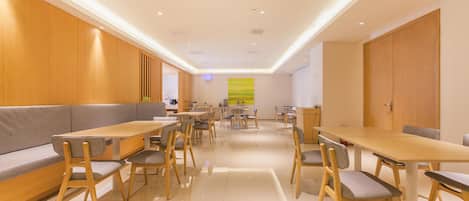 A modern dining area with wooden furniture, recessed ceiling lights, and a large window with a view.
