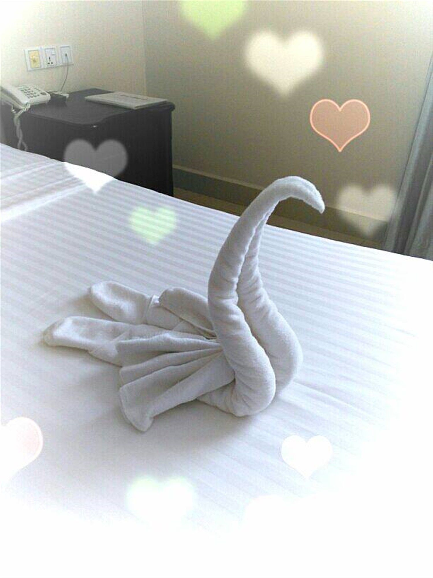 A bed with a towel arranged in the shape of a swan.
