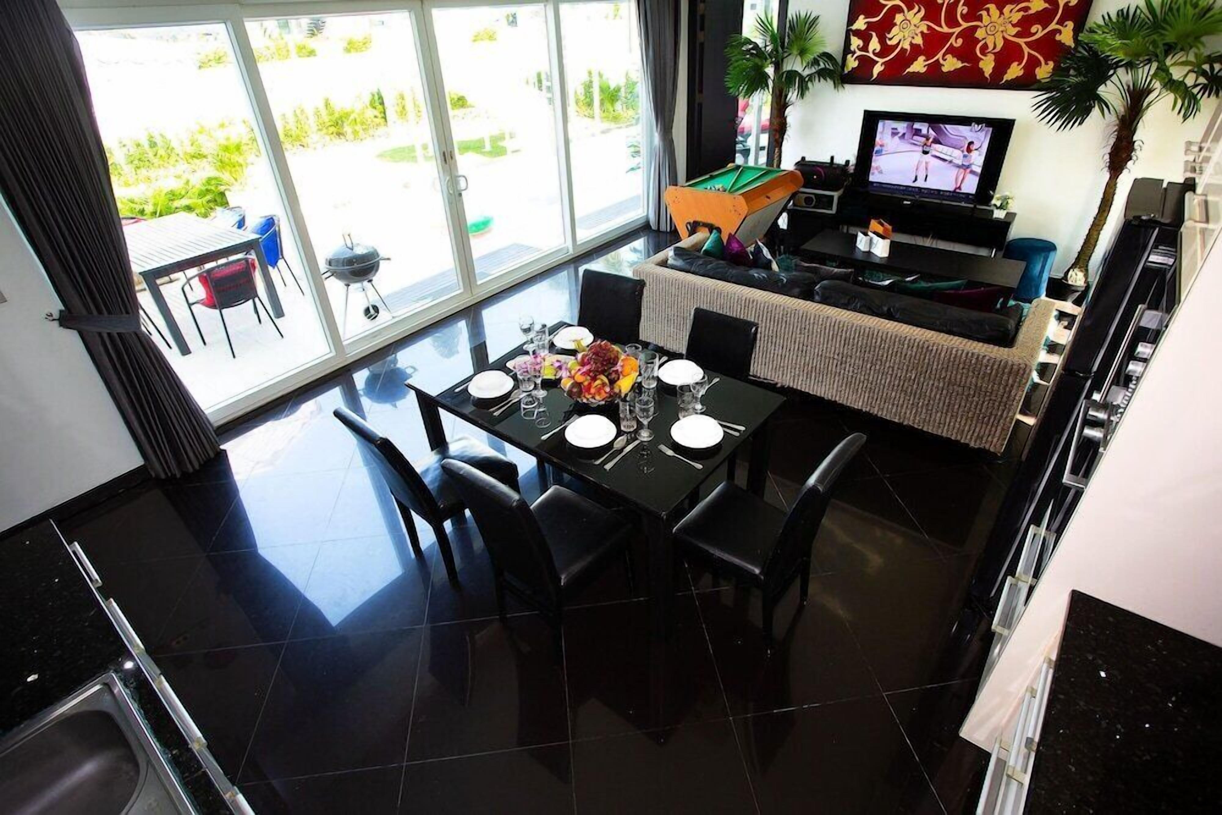 A dining area with a table set for four, a pool table, and a television in the background.