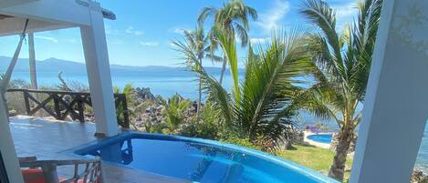 A pool area with a view of the ocean and palm trees.