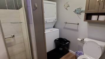 Ein modernes Badezimmer mit bodengleicher Dusche, Toilette und integriertem Waschmaschinenanschluss.