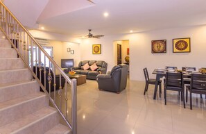 A spacious living area with a staircase, a dining table set for four, and a comfortable seating arrangement.