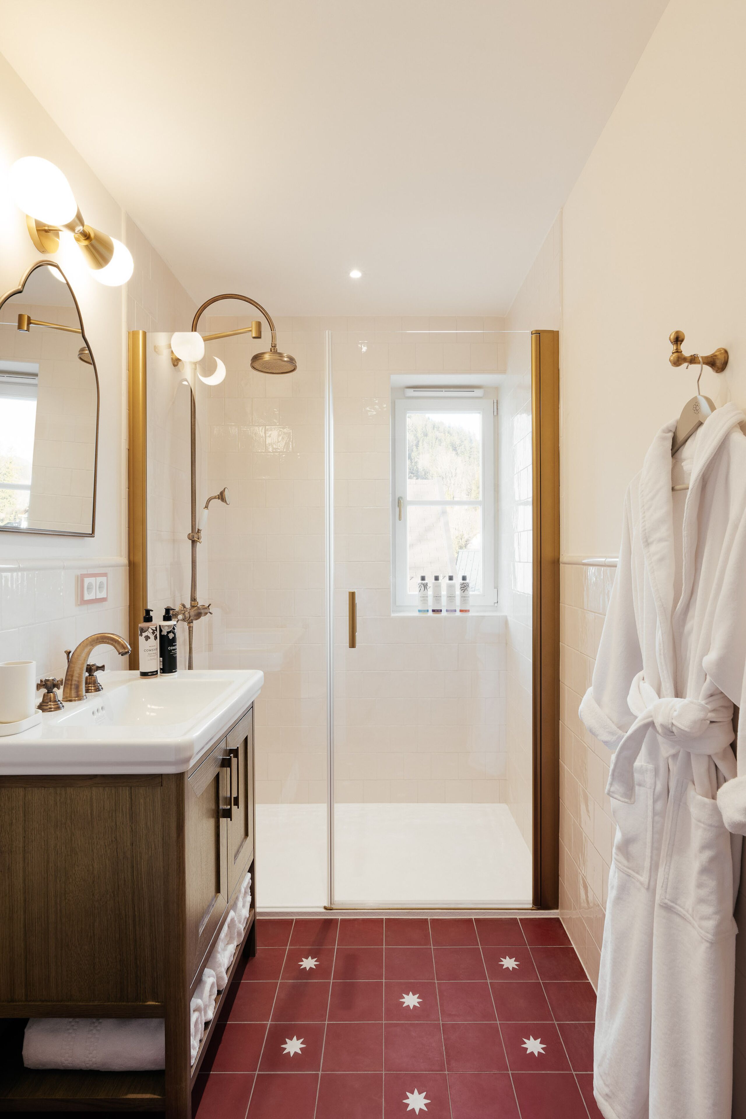 A bathroom with a white sink, vanity, and a glass shower enclosure.
