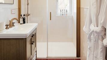 A bathroom with a white sink, vanity, and a glass shower enclosure.