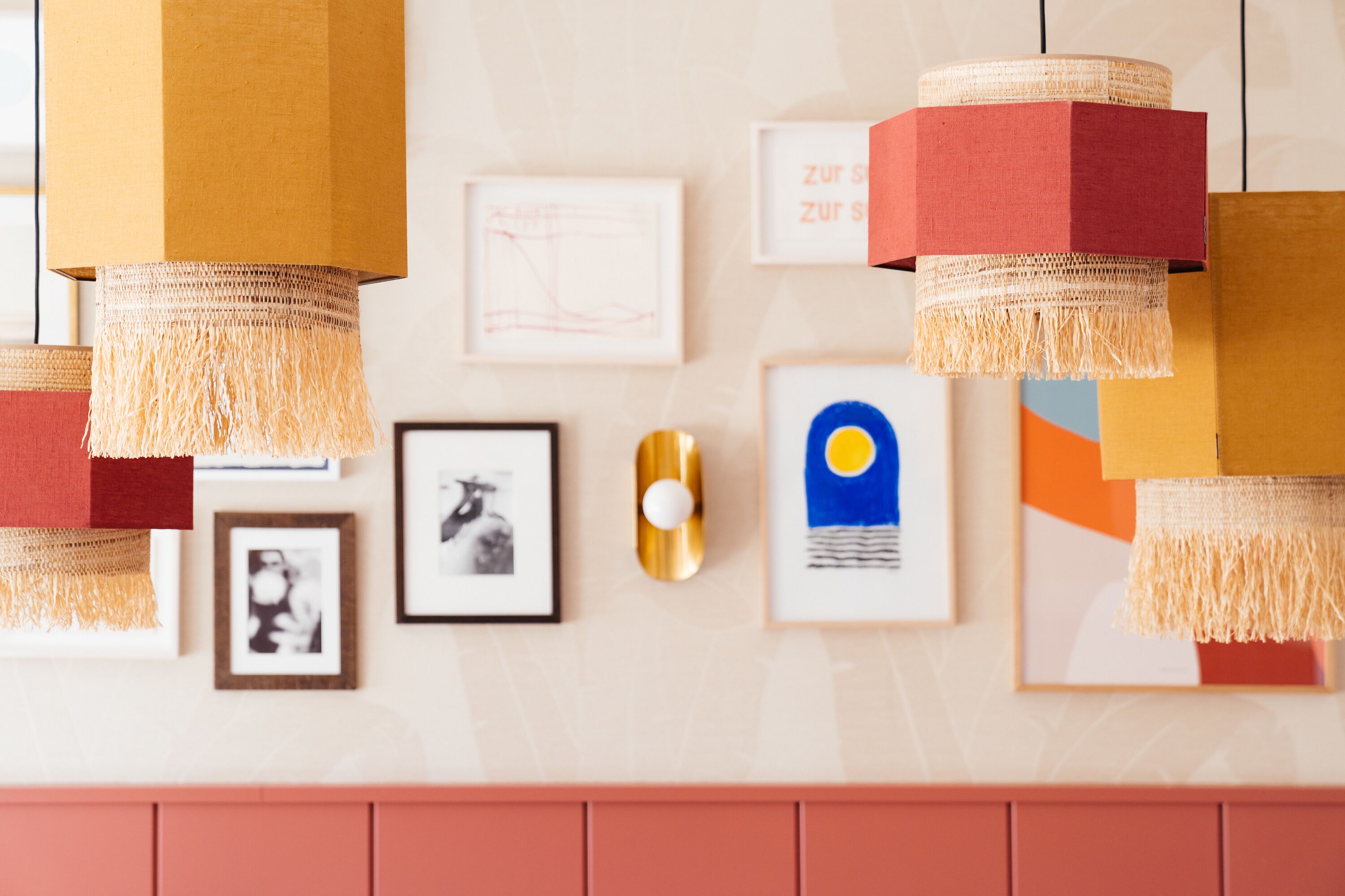 Un mur orné de tableaux encadrés, dont une œuvre aux couleurs bleue et jaune, et un objet sphérique doré.
