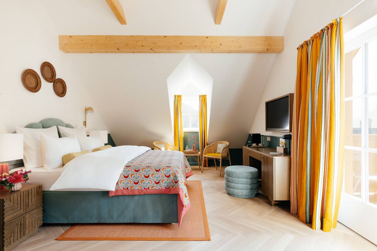 Une chambre à coucher comprenant un lit, une table de chevet, une lampe et un bureau avec une chaise.