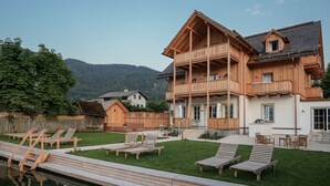 A large wooden house with a balcony, a swimming pool, and a grassy lawn. - Villa Alma - a lakeside Boutique Hotel (St. Gilgen)