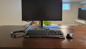 Un ordinateur installé sur un bureau en bois, avec un écran, un clavier et une souris.