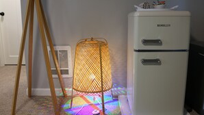 Un vieux réfrigérateur Demuller, une échelle en bois et un motif coloré projeté sur le sol.