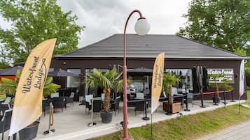 A waterfront lodge with outdoor seating and potted plants.