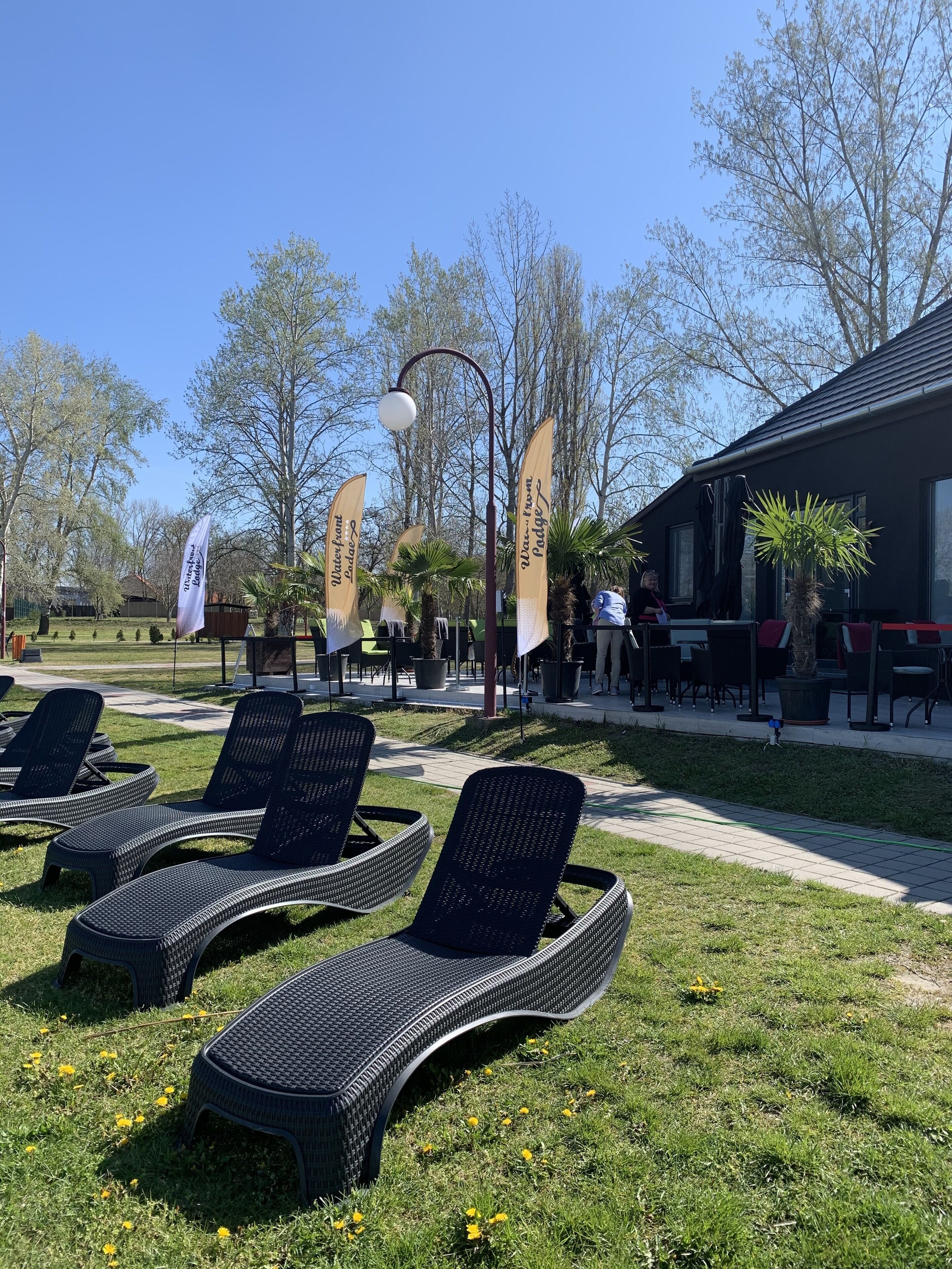 Buiten lounge stoelen, een pad en vlaggen met tekst.