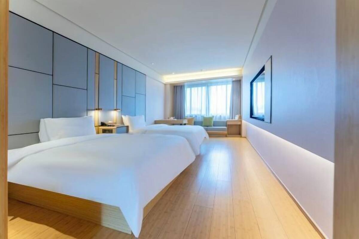 Habitació d'hotel amb un llit gran, taules de nit, un escriptori i una finestra.