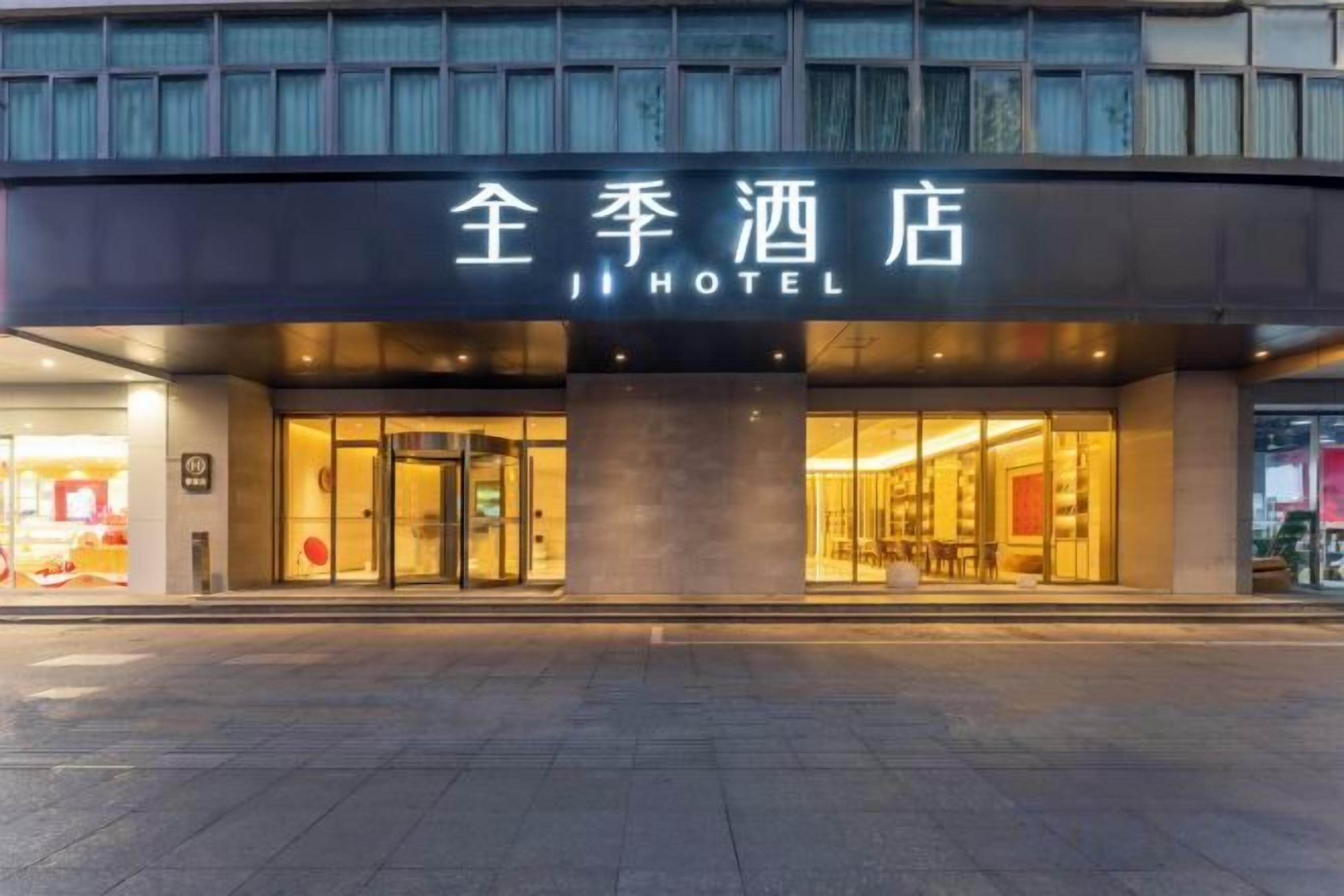 A hotel entrance with a sign that reads 'JI HOTEL' and a glass door entrance.