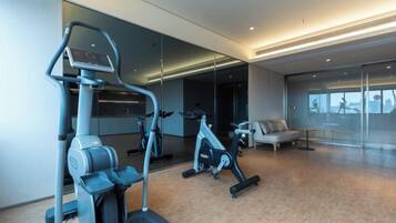 A gym with exercise equipment, a sofa, and a large window.