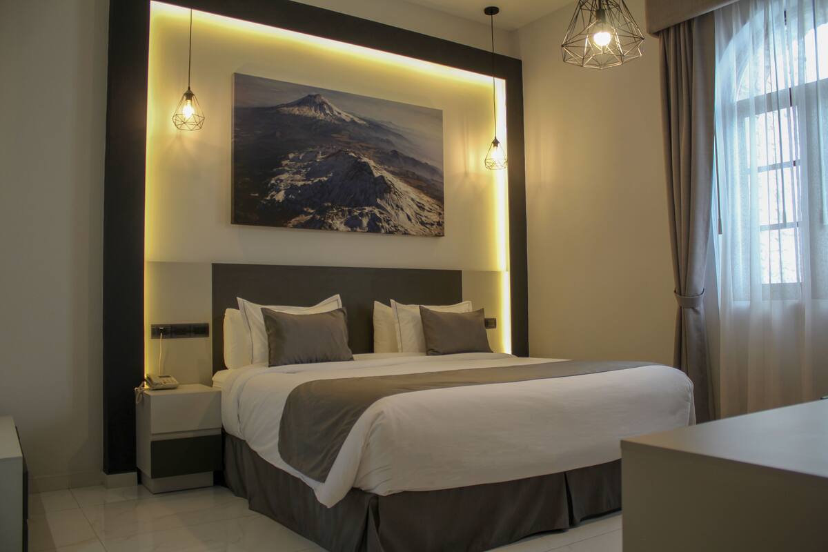 Ein modernes Hotelzimmer mit einem großen Bett, einem Nachttisch, einer Wandlampe und einem Berg.