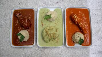 Three rectangular dishes with different sauces and garnishes on a textured surface.