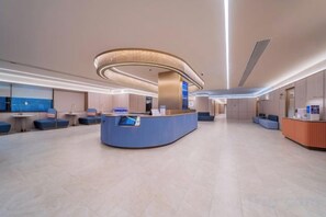 A modern hotel lobby with a reception desk, seating areas, and a large window providing a view. - HanTing Hotel (Chongqing Jiefangbei Raffles) (Chongqing)