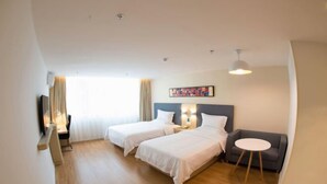 Et hotelværelse med to senge, et skrivebord, en stol, en sofa og et lille bord.