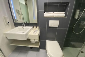 A modern bathroom with a white sink, a toilet, and a glass-enclosed shower area. - HanTing Hotel (Chongqing Jiefangbei Raffles) (Chongqing)