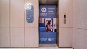 Elevatorinteriør med digitalt display der viser nummer 5, en etageindikator og en reklameplakat for Hanting Hotel.