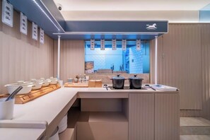 A modern kitchen with a central island, a built-in oven, and a window with hanging lights. - HanTing Hotel (Chongqing Jiefangbei Raffles) (Chongqing)